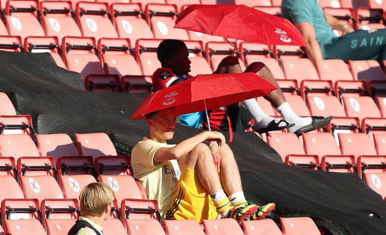 Mesut Özil versteckt sich unter einem Sonnenschirm auf der Tribüne im Spiel gegen Southampton