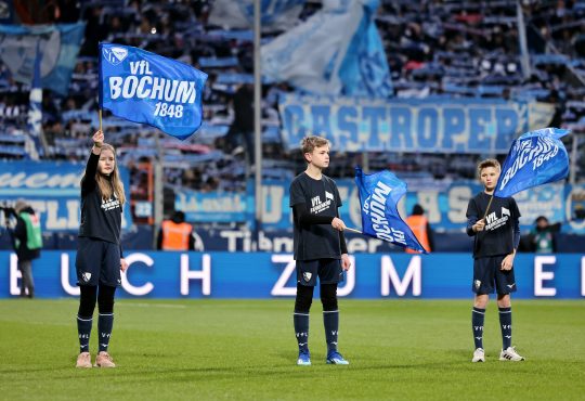 drei Kinder schwenken Bochum Fahnen beim einlaufen der Spieler