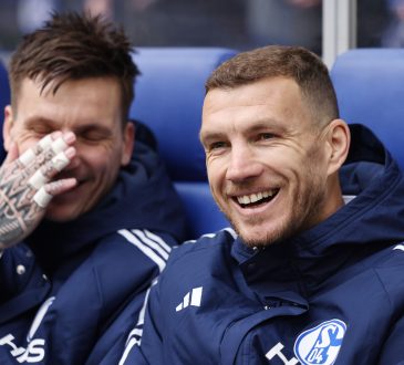 Edin Dzeko in einer Schalke 04 Trainingsjacke auf der Auswechselbank.