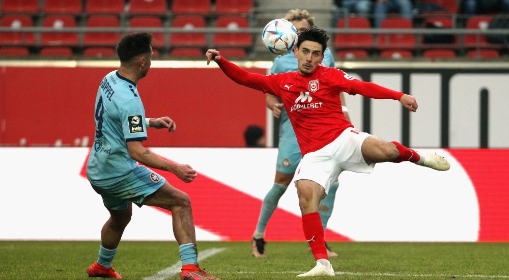 Timur Gayret nimmt einen Ball vor einem Verteidiger Volley.