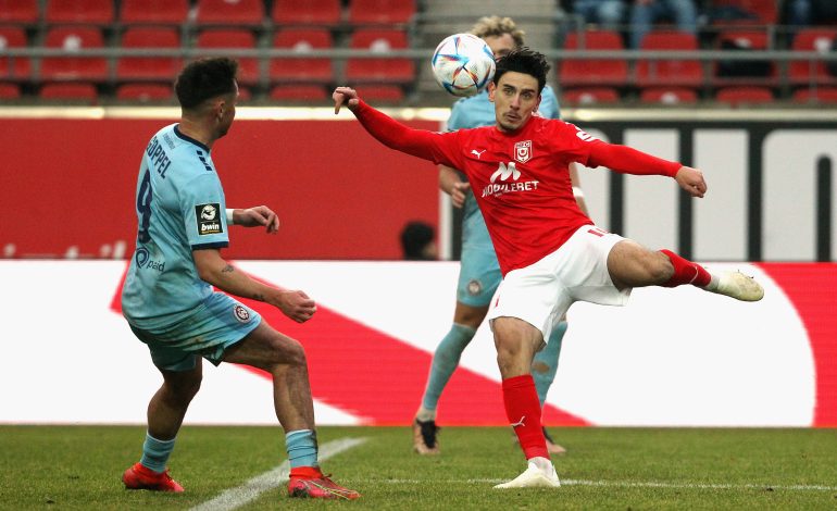 Timur Gayret nimmt einen Ball vor einem Verteidiger Volley.