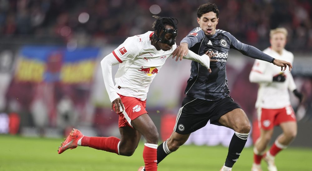 Yan Diomande von RB Leipzig läuft mit dem Ball, während er unter Druck von Farès Chaïbi von Eintracht Frankfurt steht.