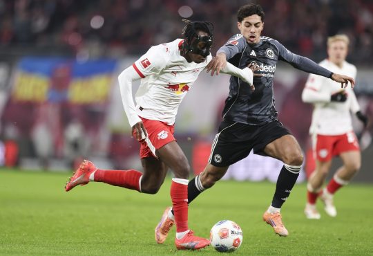 Yan Diomande von RB Leipzig läuft mit dem Ball, während er unter Druck von Farès Chaïbi von Eintracht Frankfurt steht.