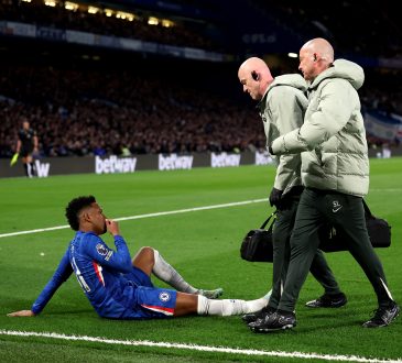 Estevao von Chelsea sitzt verletzt am Boden, zwei Betreuer gehen zu ihm.